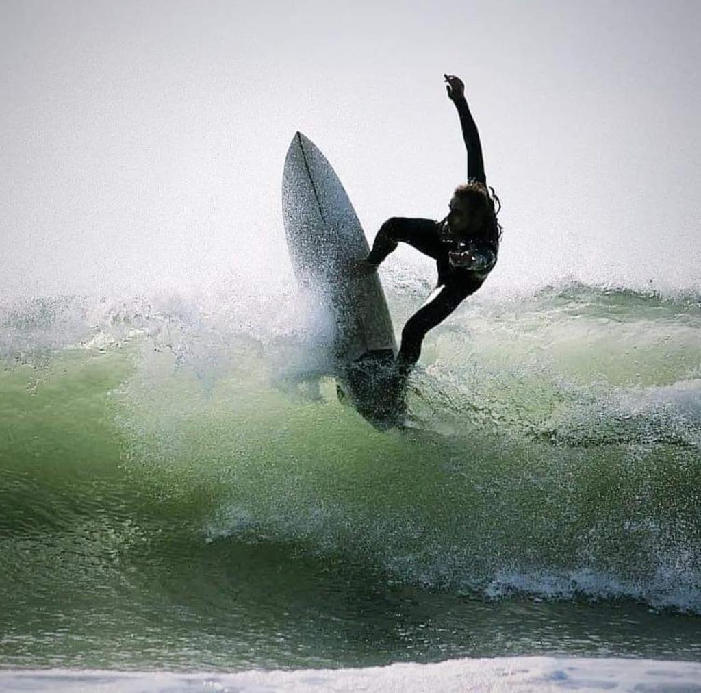 Photo d’un de nos élève qui fait une figure de surf sur la vague
